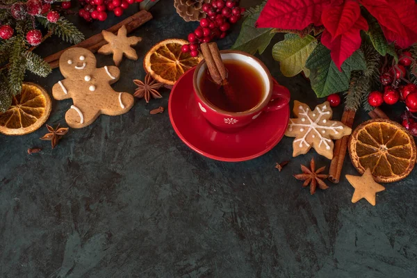 圣诞装饰 一杯香茶加香料 姜饼人饼干 深色背景的一品红 — 图库照片