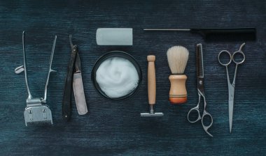 Üst düzey berber aletleri. Ustura, makas, fırça, tıraş makinesi, koyu ahşap arka planda alum, eski tarz araçlar