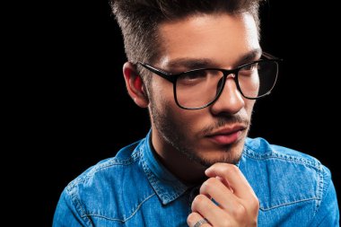 smart young man wearing denim and glasses while thinking 