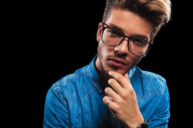 young man wearing glasses while thinking and posing 