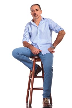 confident mature casual man posing seated on chair