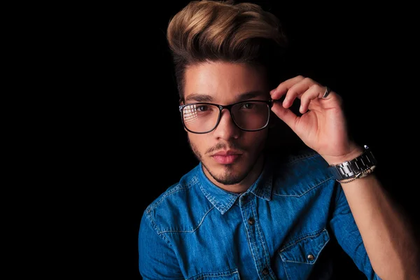 Menino vestindo jeans posando enquanto fixa seus óculos — Fotografia de Stock