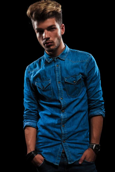 Fashionable hipster wearing denim posing in dark studio — Stock fotografie