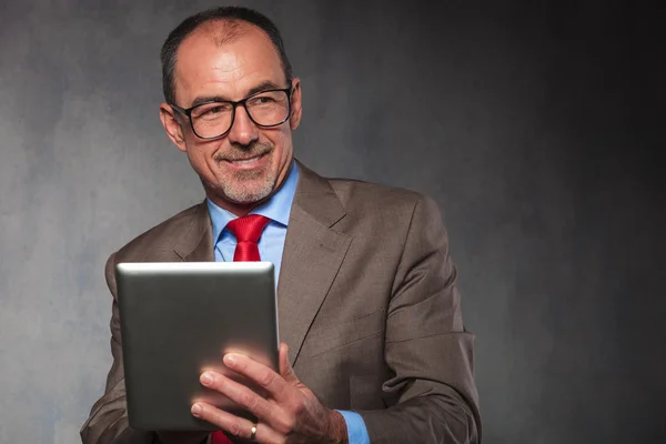 Ώριμος άνδρας με κοστούμι φοράει γυαλιά, χρήση του tablet — Φωτογραφία Αρχείου