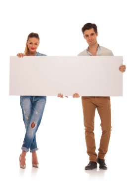 casual couple posing holding a blank billboard