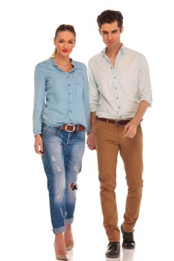 couple walking in white studio holding hands