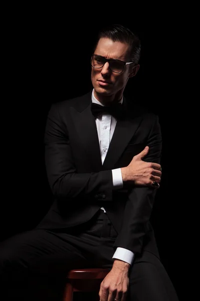 Classy man in black wearing glasses posing in dark studio — Stock Photo, Image