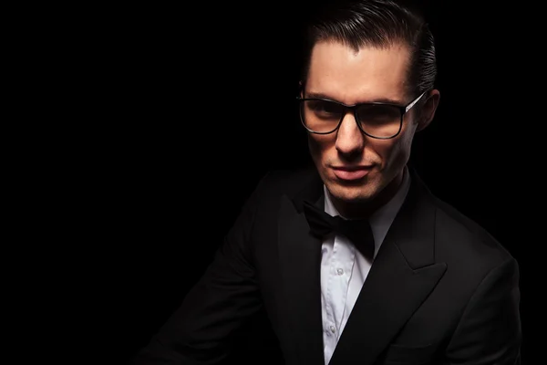 Smart affärsman i svart kostym poserar i mörka studio — Stockfoto