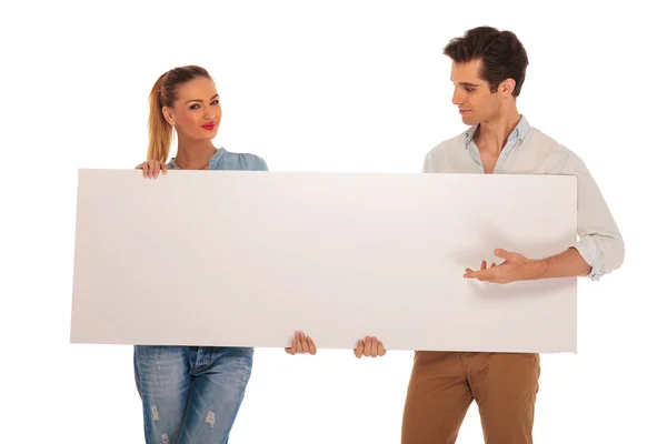 Bonito casal segurando um branco em branco sinal no estúdio — Fotografia de Stock