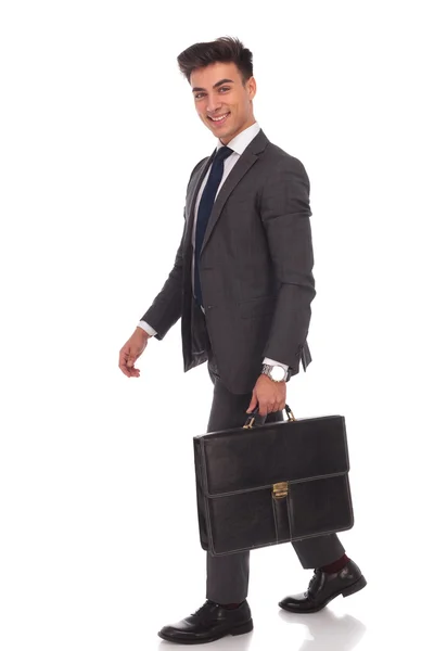 Смеющийся молодой бизнесмен идет с чемоданом — стоковое фото
