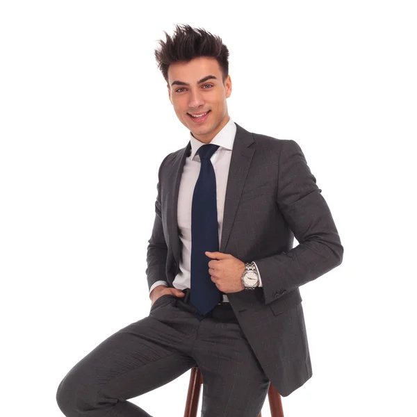 Happy young business man sitting on a chair and smiles — Stock Photo, Image