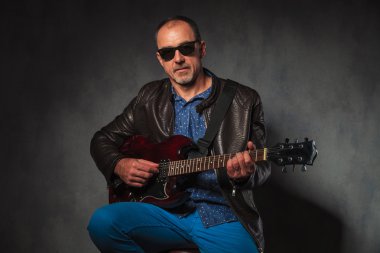 mature rocker in leather jacket playing electric guitar