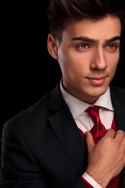 Young classy male in black suit fixing his tie — Stok fotoğraf