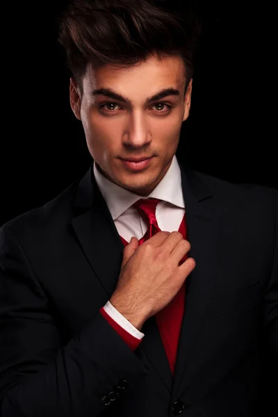 Male model in black suit fixing his red tie — 图库照片