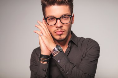 avuç içi bir arada yüzünü tutan gözlüklü adam