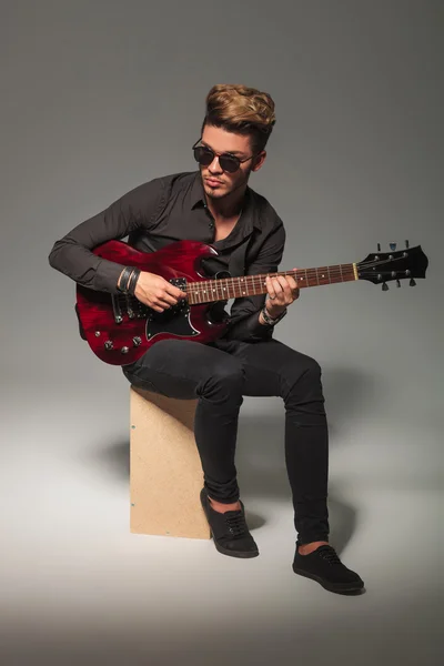 Joven guitarrista sentado en caja de madera — Foto de Stock