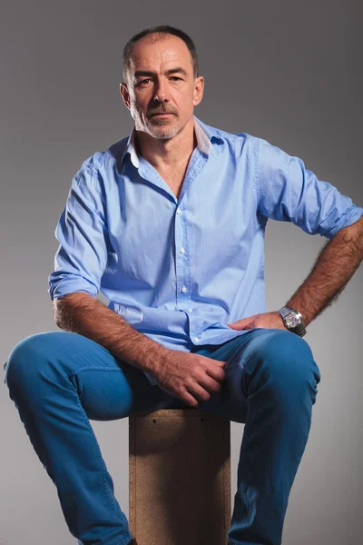 Portrait of seated mature bearded man in jeans — Stock Photo, Image