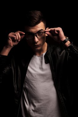 fashionable man in black leather taking off his glasses 