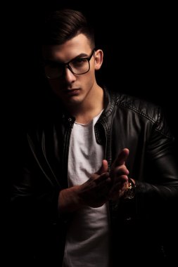dark haired man in black leather jacket, rubbing palms