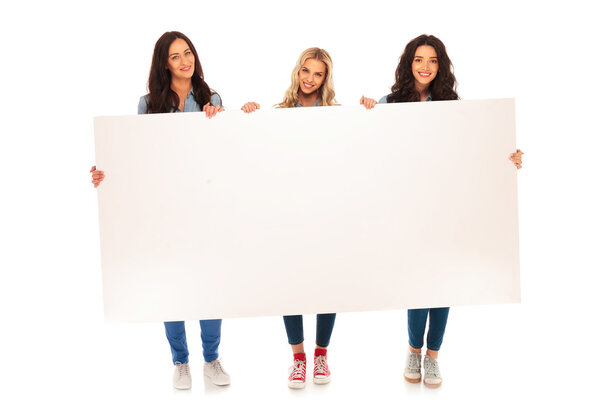 full body picture of three  casual women holding big billboard