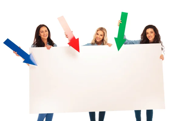 3 women presenting big board by pointing arrows to it — Stock Photo, Image