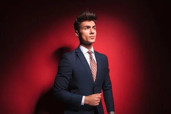 Young businessman in black with red tie arranging his jacket — Stockfoto