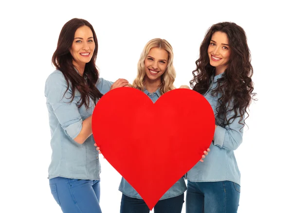 3 leende kvinnor som erbjuder sina stora röda hjärta till dig — Stockfoto