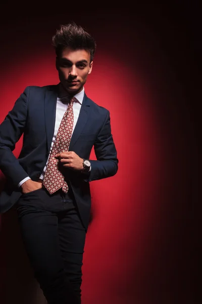 Young businessman standing in red studio with hand in pocket — Stock fotografie