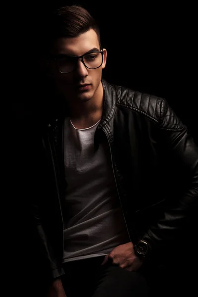 dark haired man in leather wearing frames, resting