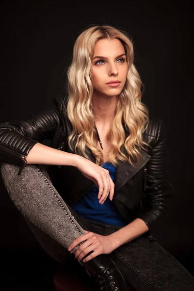 Side view of a blond woman in leather jacket sitting — Stock Photo, Image