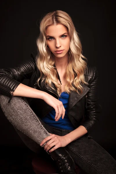 Blonde biker woman in leather jacket resting hand on knee — Stock Photo, Image