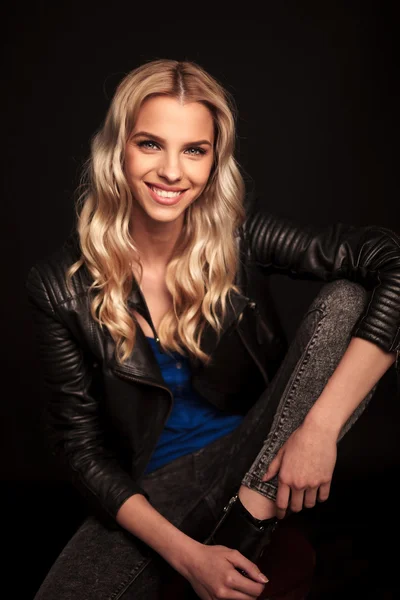 Sitzende junge blonde Frau in Lederjacke lacht — Stockfoto