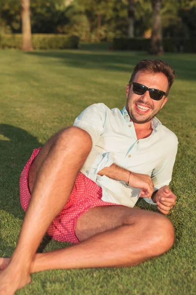 Молодой человек, лежащий в траве и смеющийся — стоковое фото