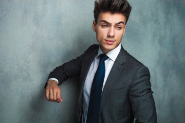 rahat işadamı dirseğinden gri bir duvara yaslanmış 