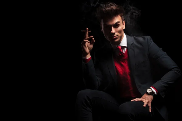 Takım elbise ve kravat sigarasını tadını zarif adam oturmuş — Stok fotoğraf