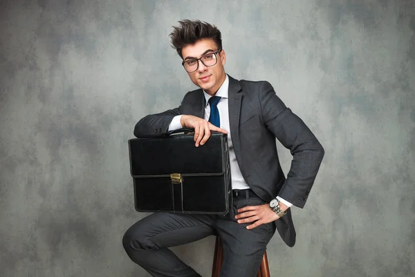 Relajado hombre de negocios sosteniendo una maleta está sentado — Foto de Stock