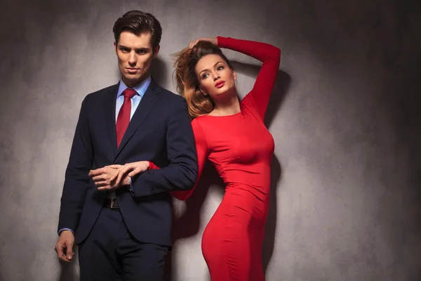 Donna in abito rosso che fissa i capelli mentre tiene il suo uomo — Foto Stock