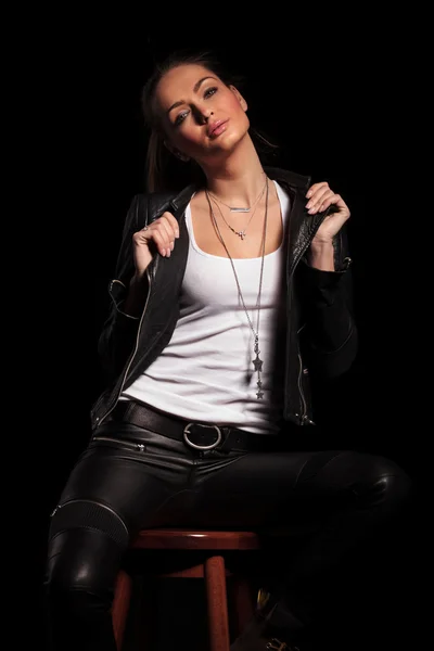 Woman in leather clothes is pulling her collar and sits — Stock Photo, Image