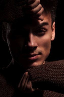 siyah arka plan üzerinde elleriyle yüzünü kaplayan adam