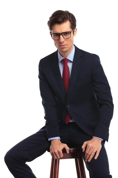 Relaxado jovem homem de negócios usando óculos está sentado — Fotografia de Stock