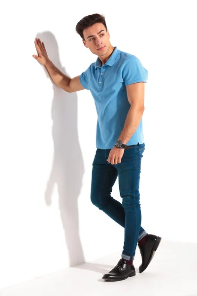 Casual man in blue polo shirt, leaning against studio wall — Stock Photo, Image
