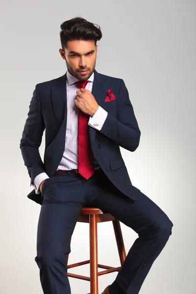 Sentado elegante hombre de negocios fijación de su corbata — Foto de Stock