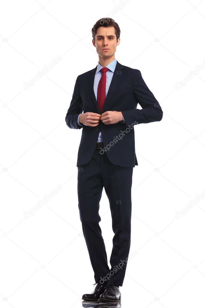 serious businessman in suit and tie buttoning coat