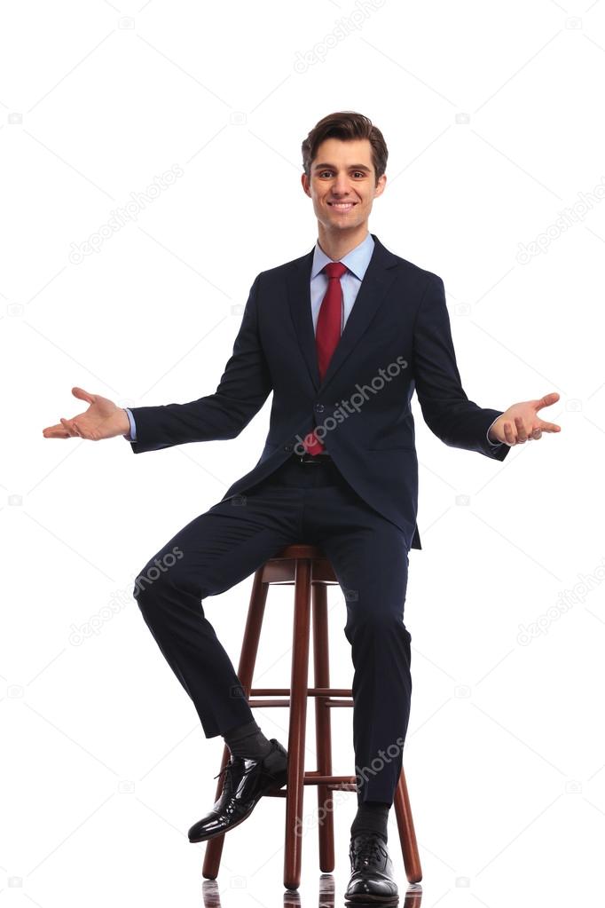 young happy business man sitting on chair and welcoming you