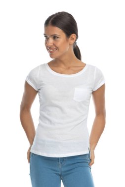 Beyaz stüdyo arka planında dikilirken gülümseyen ve başka tarafa bakan sıradan bir kadın.