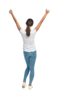 Elleri havada kutlama yapan, beyaz stüdyo arka planında duran sıradan bir kadının arka plan görüntüsü.