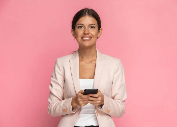 Krásná Podnikatelka Textové Telefonu Usmívá Kameru Růžovém Pozadí — Stock fotografie