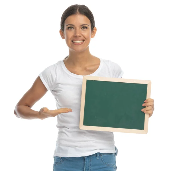 Mulher Casual Positiva Sorrindo Apresentando Quadro Negro Enquanto Estava Fundo — Fotografia de Stock