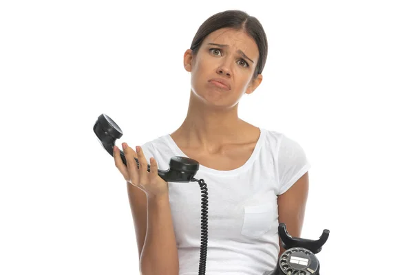 白いスタジオの背景に立っている間に古い電話で話す悲しいカジュアルな女性 — ストック写真