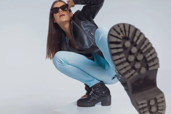 Encantadora Modelo Moda Ajustando Gafas Sol Pateando Con Pierna Agachándose — Foto de Stock